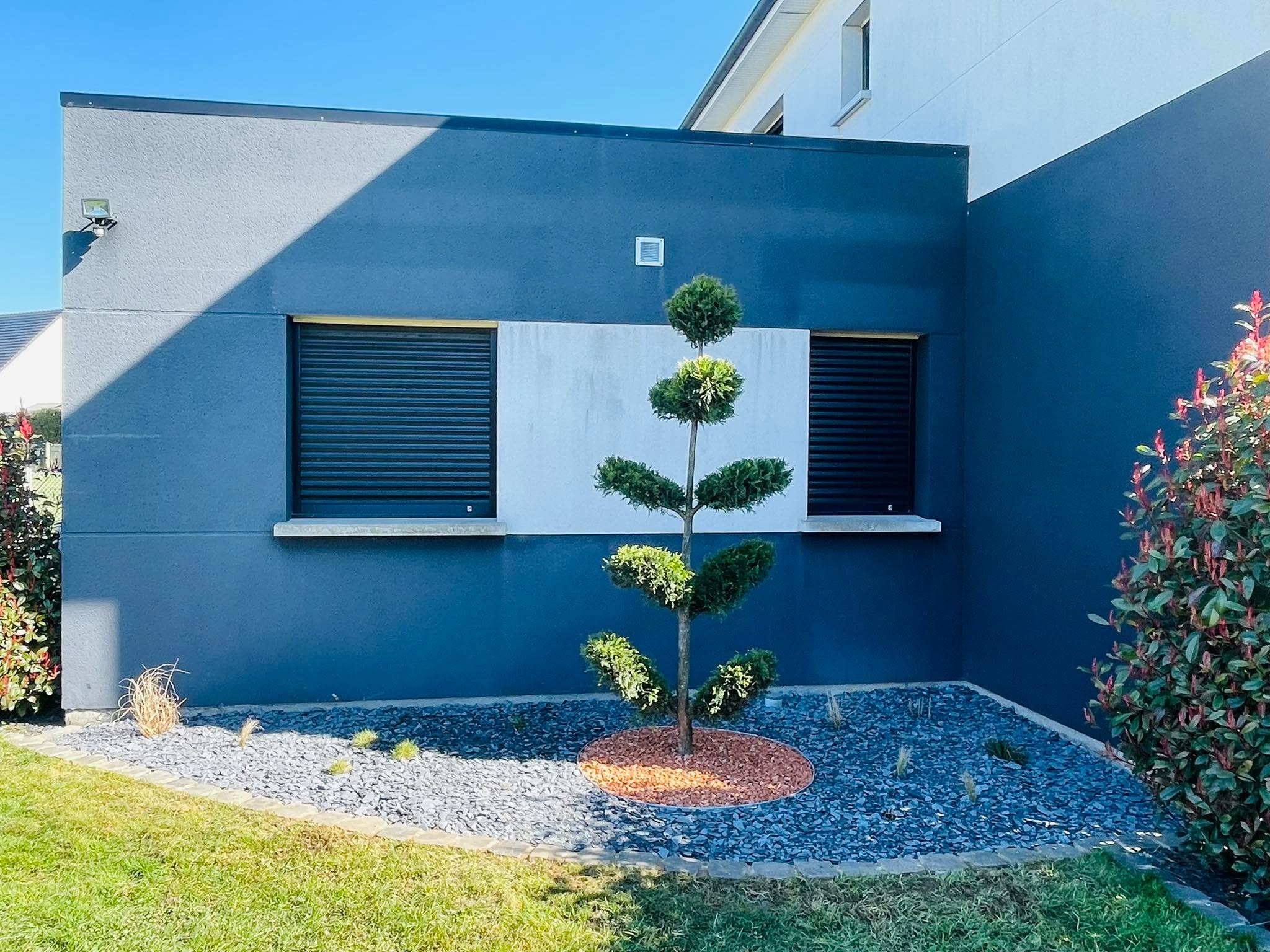 Massif minéral et conifère taillé en nuage devant une façade, aménagement réalisé par CONFORT O JARDIN