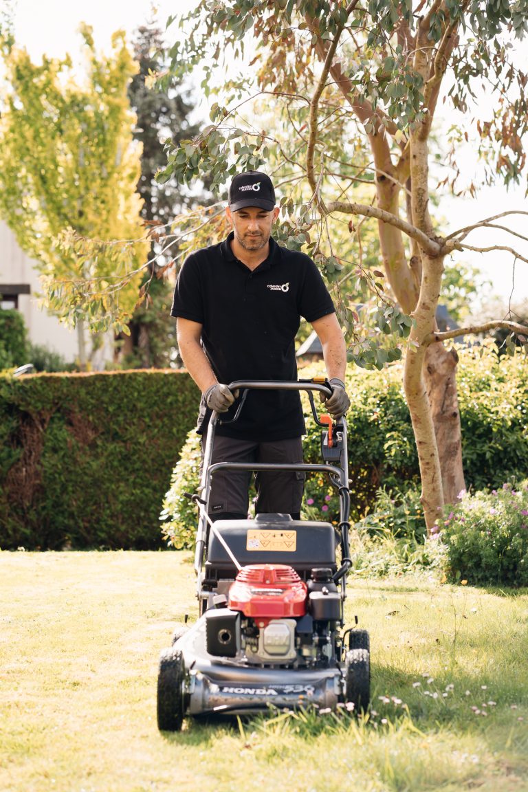 Benjamin Egret tond la pelouse d’un jardin arboré avec une tondeuse thermique Honda