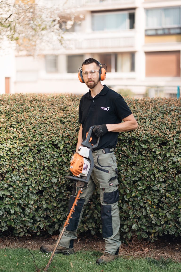 Stéphane, équipé de son taille-haie thermique STIHL, devant une haie fraîchement taillée