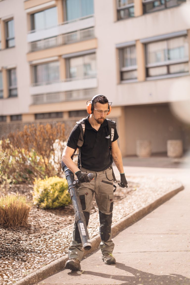 Stéphane, souffleur à dos, nettoie l’allée piétonne d’une résidence