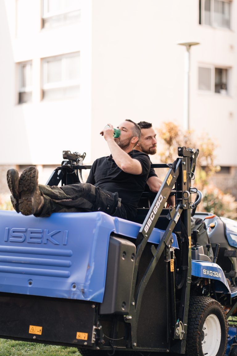 Stéphane, allongé sur le bac de la tondeuse autoportée ISEKI, et Benjamin Egret font une pause