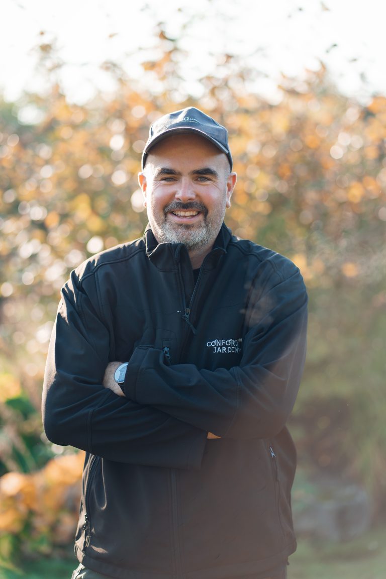 Portrait de Renaud, chef d’équipe chez CONFORT O JARDIN, bras croisés dans un jardin en automne