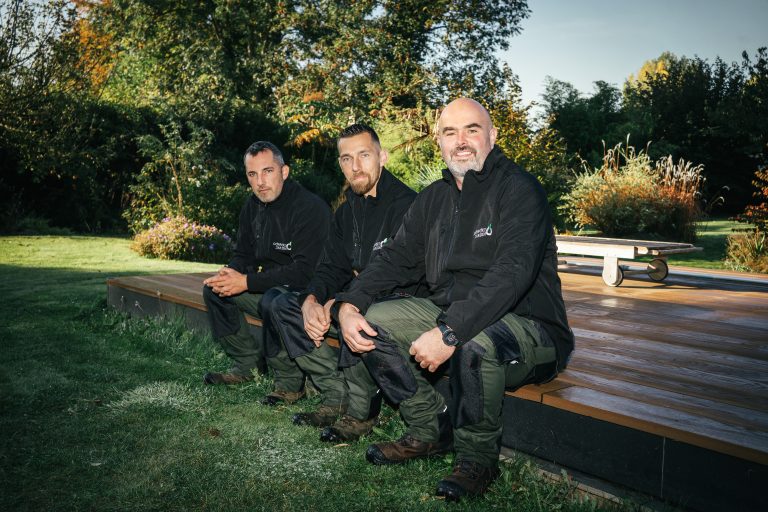 Benjamin Egret, Stéphane et Renaud, paysagistes CONFORT O JARDIN, assis au bord d’une terrasse en bois