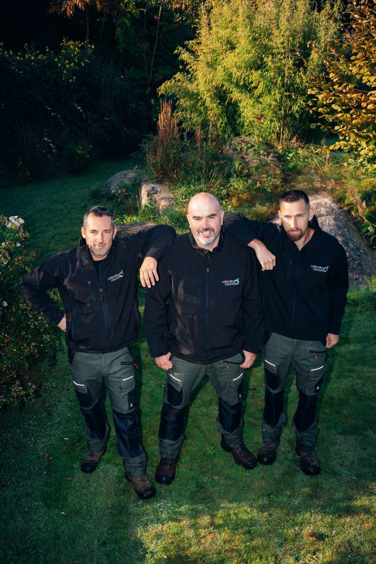 Benjamin Egret, Renaud et Stéphane, bras sur les épaules, posent dans un jardin