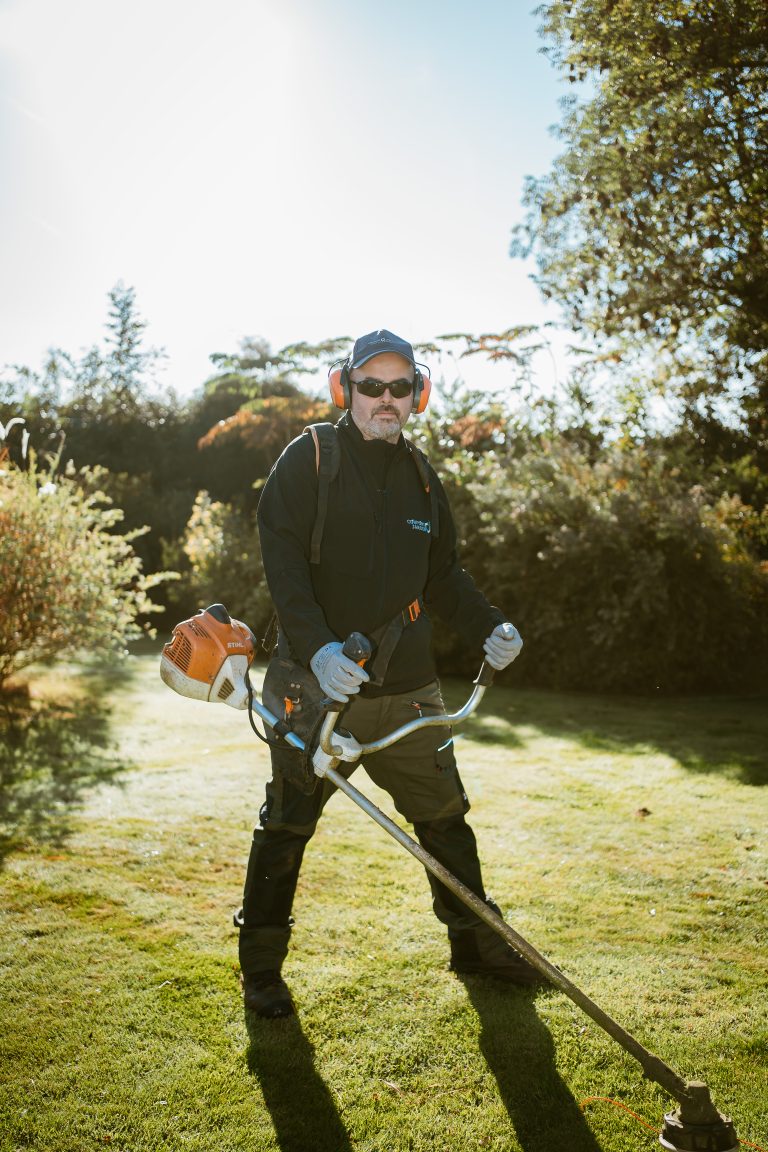 Renaud, harnais sur le dos et débroussailleuse thermique STIHL en main, dans un jardin paysager