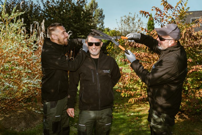 Renaud, Benjamin Egret et Stéphane plaisantent avec une cisaille à haie dans un jardin