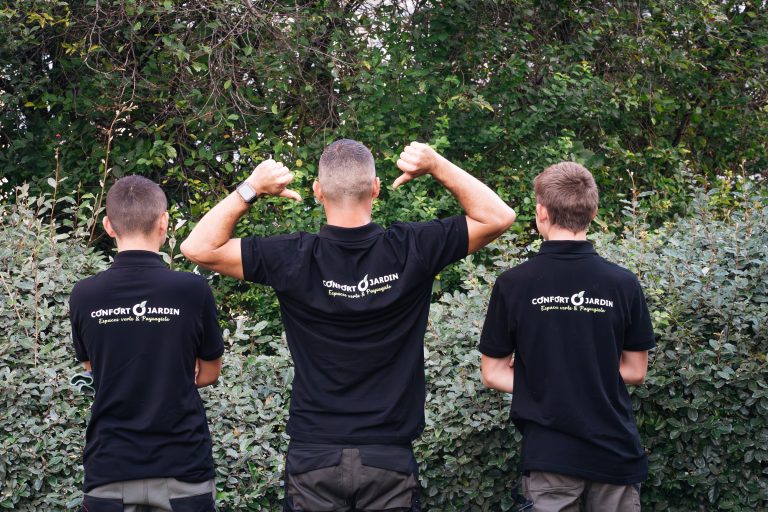 Yoni, Benjamin Egret et Louka de dos, désignant le logo CONFORT O JARDIN sur leur polo
